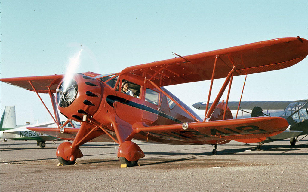 Waco with engine running at tie downs on tarmac